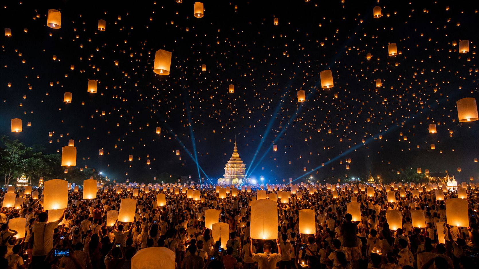 Multitud bajo un cielo de linternas durante Yi Peng en Chiang Mai