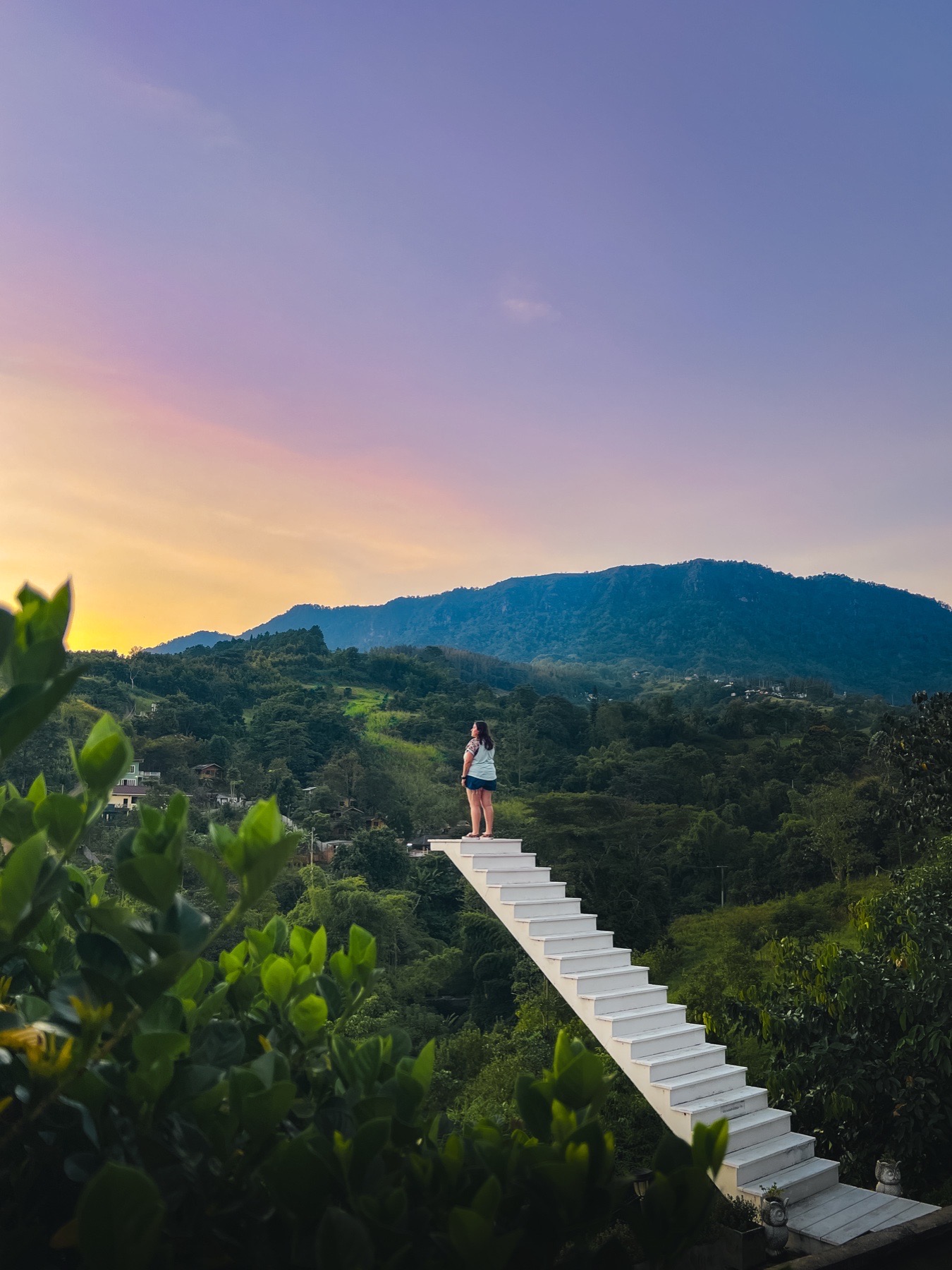 Viajera contemplando las montañas desde una escalera en Tailandia